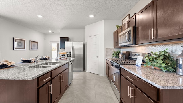 kitchen with stainless steel appliances, dark brown cabinets, sink, and backsplash