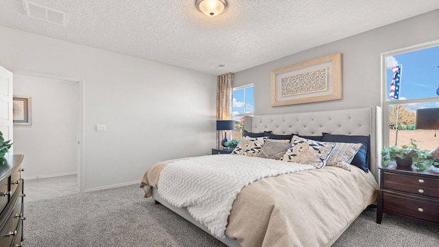 bedroom with light colored carpet and a textured ceiling