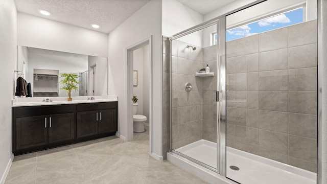 bathroom featuring tile patterned flooring, vanity, an enclosed shower, toilet, and a textured ceiling