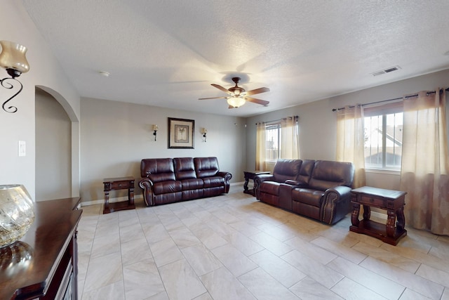 living room with light tile patterned flooring, a textured ceiling, and ceiling fan