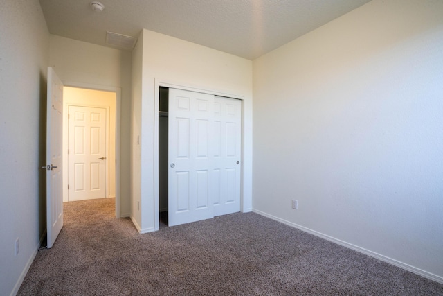 unfurnished bedroom featuring a closet and dark colored carpet