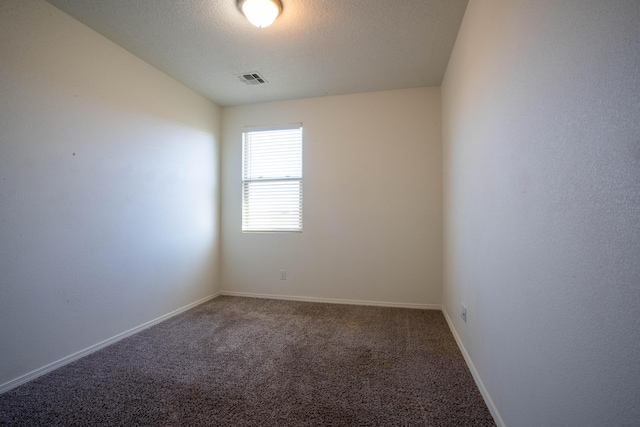 empty room featuring a textured ceiling and dark colored carpet