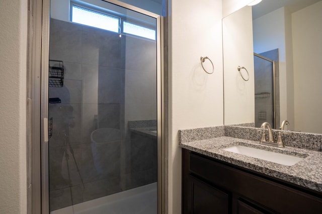 bathroom featuring a shower with shower door and vanity