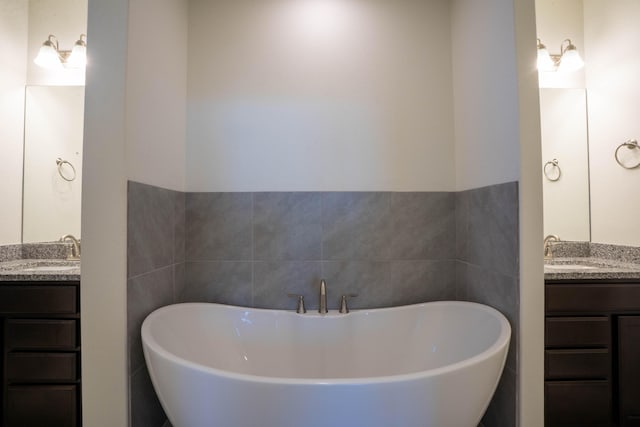 bathroom featuring vanity, a bath, and tile walls