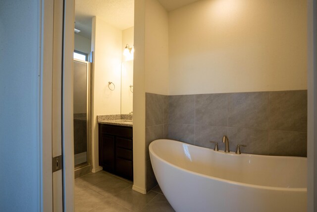 bathroom with tile walls, plus walk in shower, vanity, and tile patterned flooring