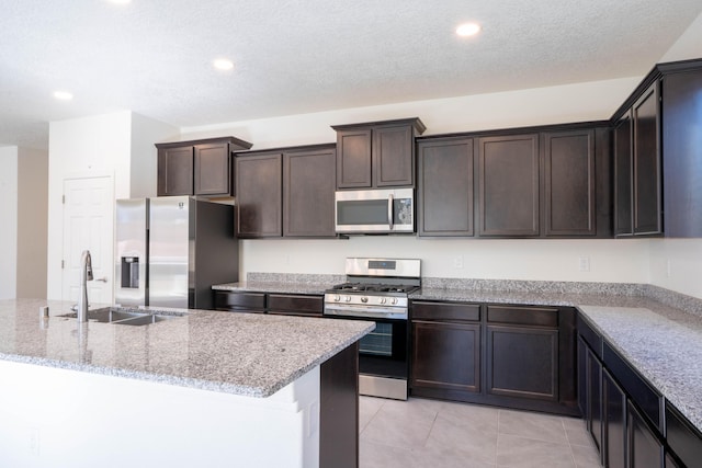 kitchen with sink, stainless steel appliances, light stone countertops, and light tile patterned flooring