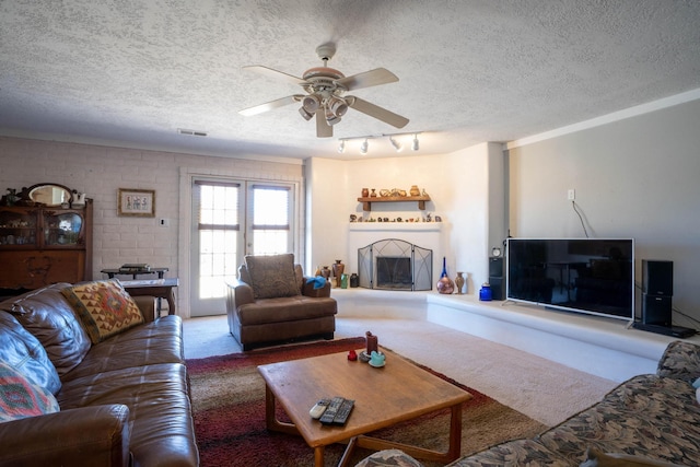 carpeted living room featuring ceiling fan and a textured ceiling