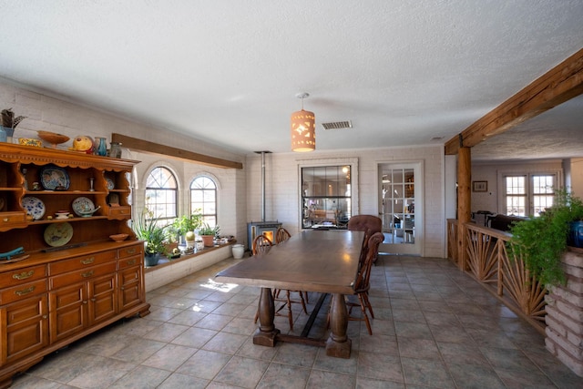 dining area featuring french doors, tile patterned flooring, a textured ceiling, and a wood stove