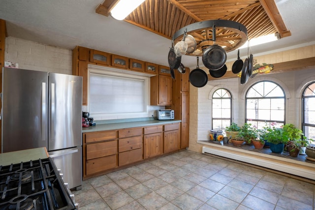 kitchen featuring a healthy amount of sunlight, stainless steel fridge, gas range oven, and a baseboard heating unit