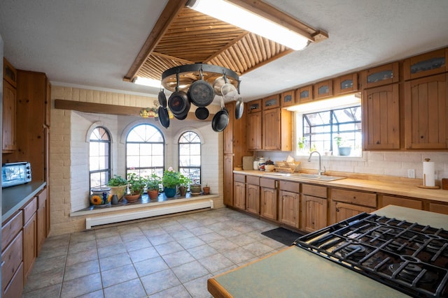 kitchen with tasteful backsplash, a baseboard radiator, sink, and a textured ceiling