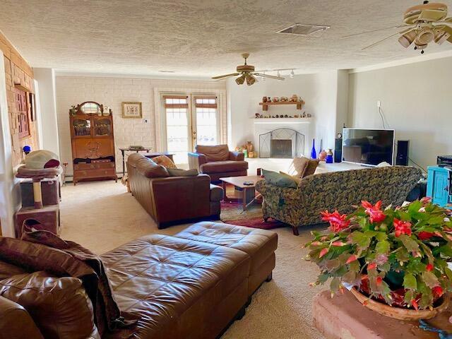 living room featuring light carpet, a textured ceiling, and ceiling fan