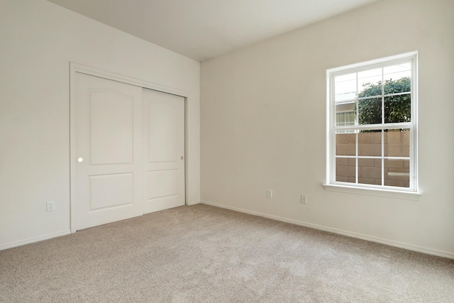 unfurnished bedroom with a closet and light carpet