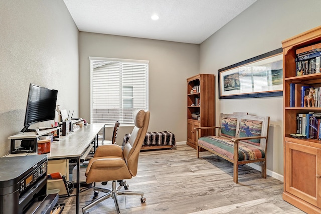 home office with light wood-style flooring, baseboards, and a textured ceiling