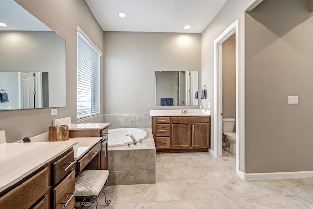 bathroom featuring a relaxing tiled tub, vanity, and toilet