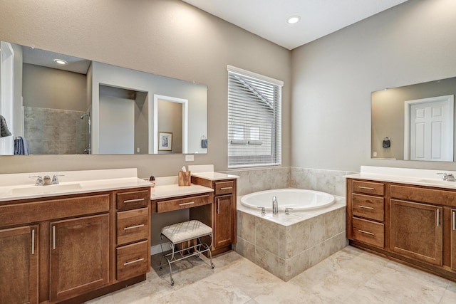 bathroom featuring a garden tub, a stall shower, two vanities, and a sink