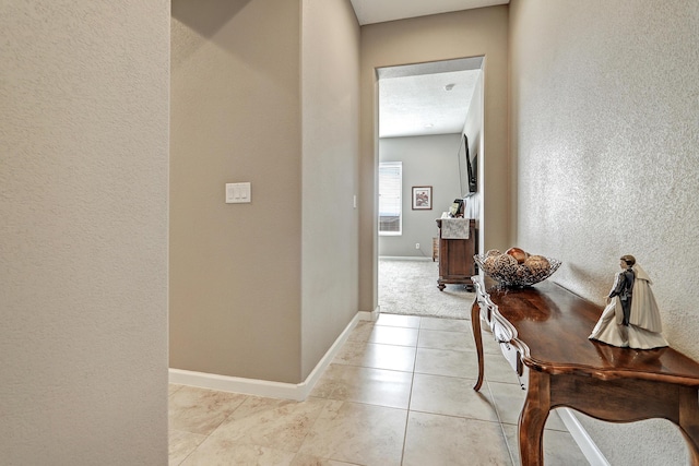 corridor featuring light tile patterned floors and a textured ceiling