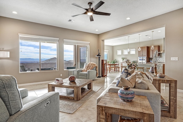 tiled living room with ceiling fan and a textured ceiling