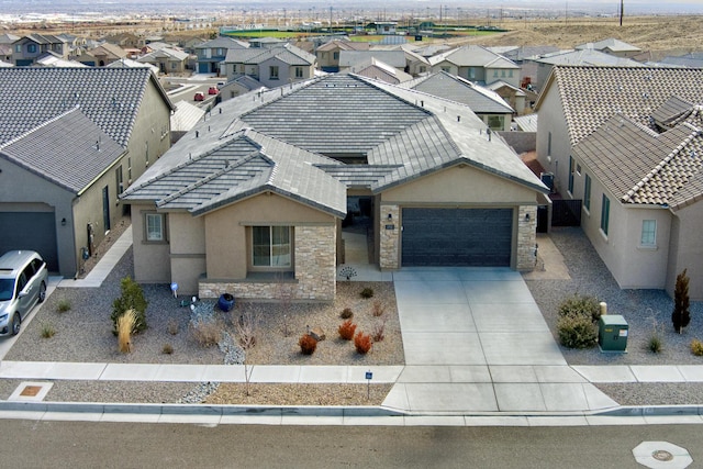 view of front of home with an attached garage, stone siding, a residential view, and stucco siding