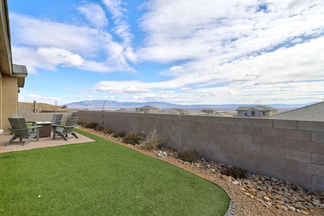 view of yard featuring a fenced backyard, a patio, and a mountain view