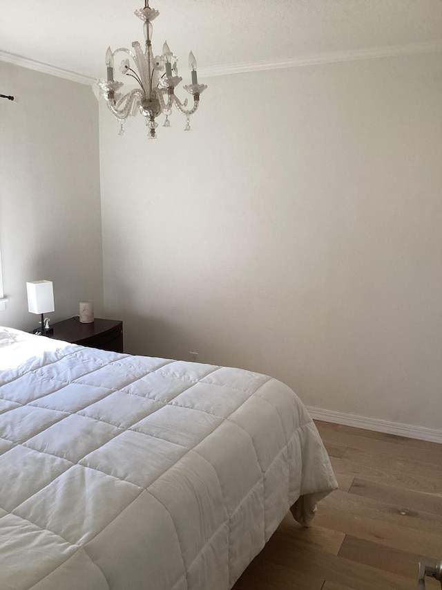 bedroom with crown molding, wood-type flooring, and an inviting chandelier