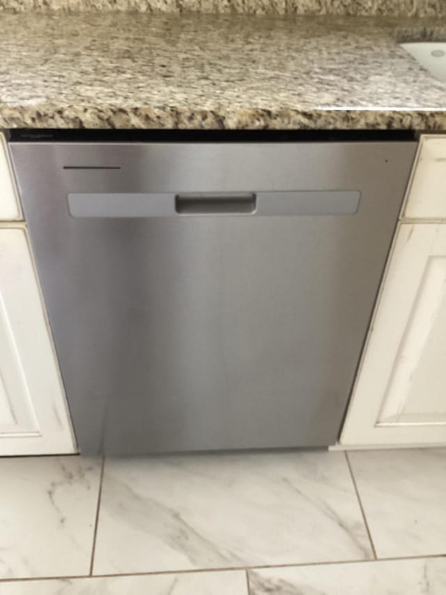 interior details with white cabinetry, light stone counters, and stainless steel dishwasher