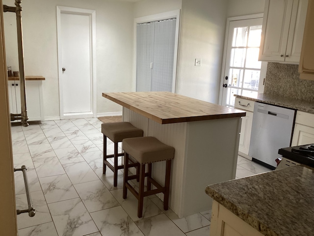 kitchen with a breakfast bar, wooden counters, a center island, dishwasher, and backsplash