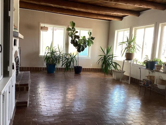 interior space with a fireplace, wooden ceiling, beamed ceiling, and a healthy amount of sunlight