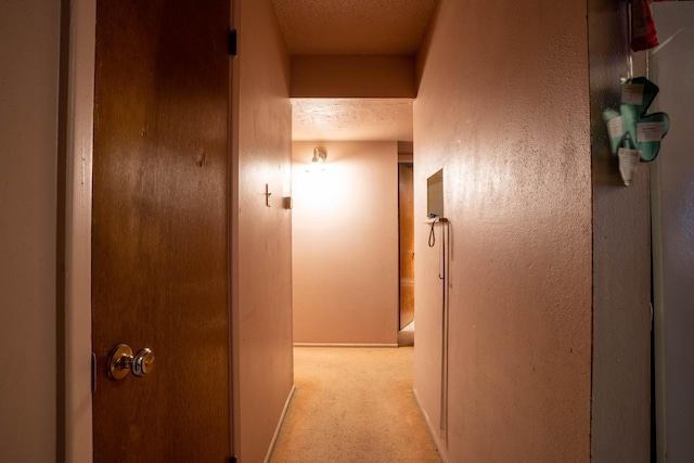 hallway with light colored carpet and a textured ceiling