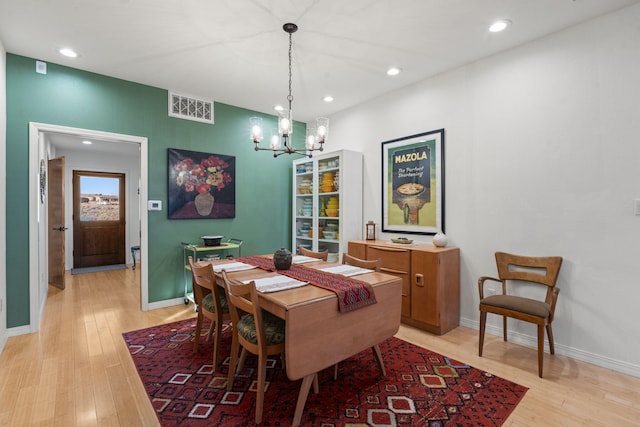 dining room with light hardwood / wood-style floors and a chandelier