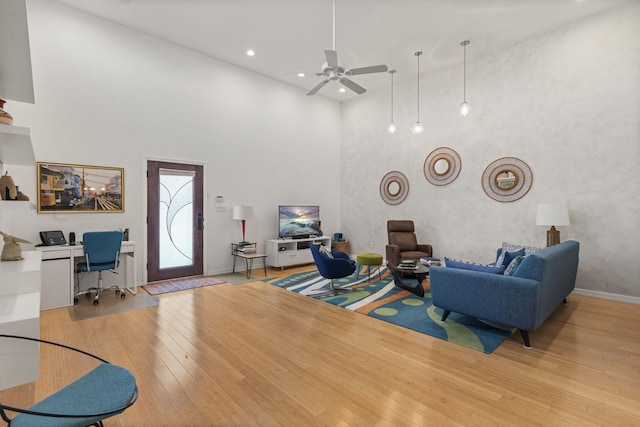 living room featuring a towering ceiling, ceiling fan, and light hardwood / wood-style flooring