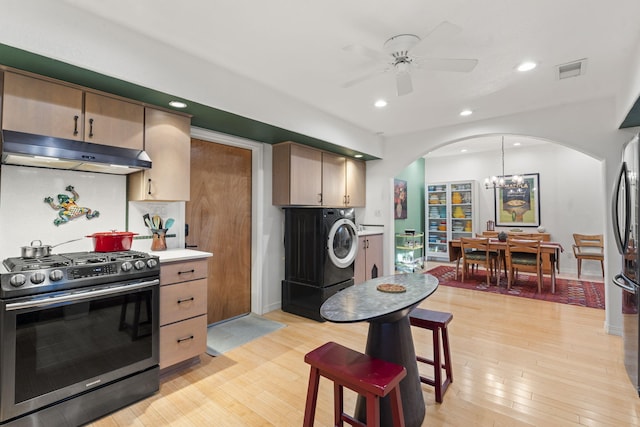 kitchen with pendant lighting, stainless steel gas stove, light hardwood / wood-style floors, washer / clothes dryer, and decorative backsplash