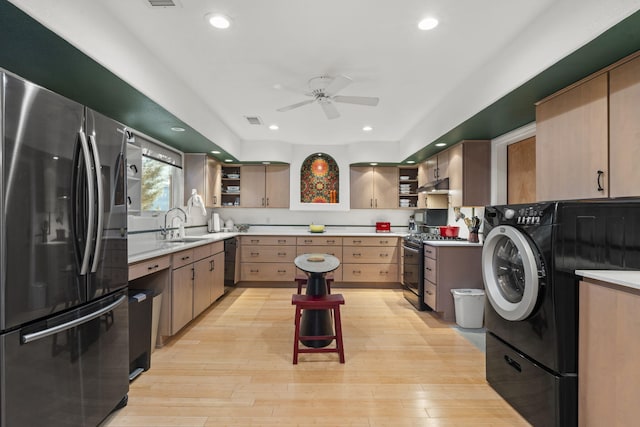 kitchen with sink, light brown cabinets, stainless steel appliances, washer / clothes dryer, and light hardwood / wood-style floors