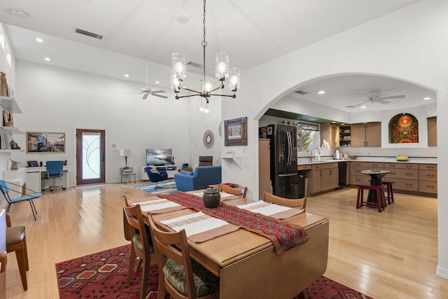 dining room featuring sink, ceiling fan with notable chandelier, and light wood-type flooring