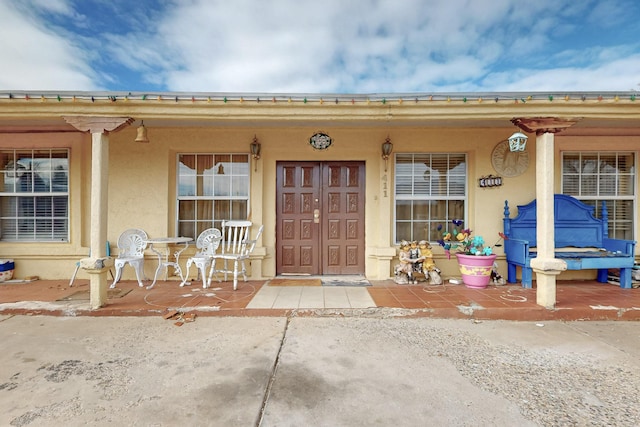 property entrance with a porch and stucco siding