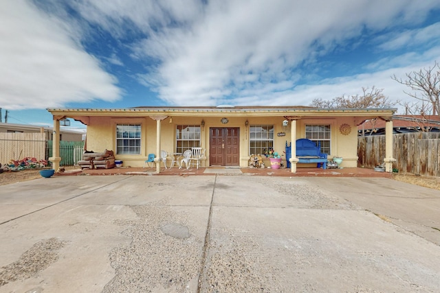 view of front of property featuring covered porch, fence, and stucco siding