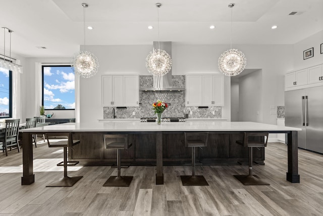 kitchen featuring a large island, built in fridge, and white cabinets