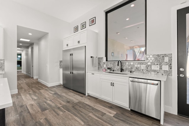 kitchen with sink, decorative backsplash, stainless steel appliances, and white cabinets