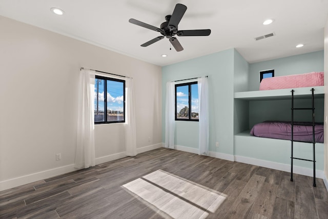 unfurnished bedroom with multiple windows, hardwood / wood-style flooring, and ceiling fan