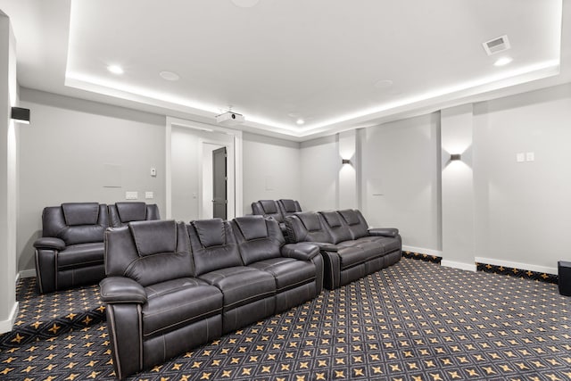 cinema room featuring a raised ceiling and carpet