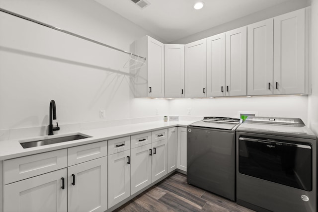 laundry room featuring separate washer and dryer, sink, dark hardwood / wood-style flooring, and cabinets