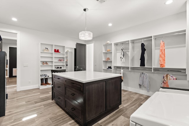 spacious closet with independent washer and dryer and light hardwood / wood-style flooring