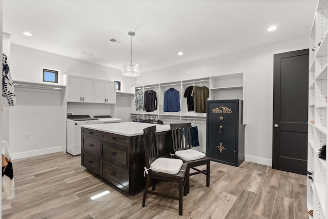 kitchen with decorative light fixtures, light hardwood / wood-style flooring, independent washer and dryer, and white cabinets