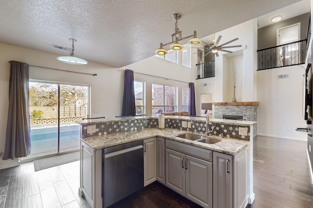 kitchen featuring sink, hanging light fixtures, light stone countertops, and stainless steel dishwasher