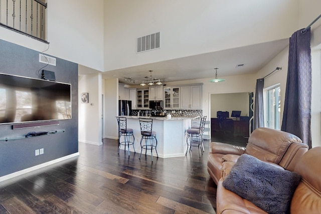 living room with a towering ceiling and dark hardwood / wood-style floors