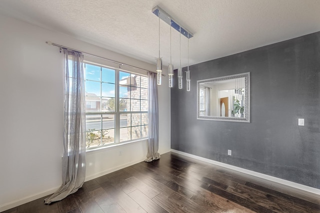 unfurnished dining area featuring dark wood-type flooring, a textured ceiling, and plenty of natural light