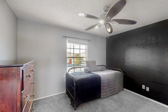 bedroom with ceiling fan, light colored carpet, and a textured ceiling