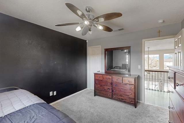 carpeted bedroom featuring ceiling fan and a textured ceiling