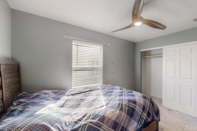 carpeted bedroom with a textured ceiling, a closet, and ceiling fan