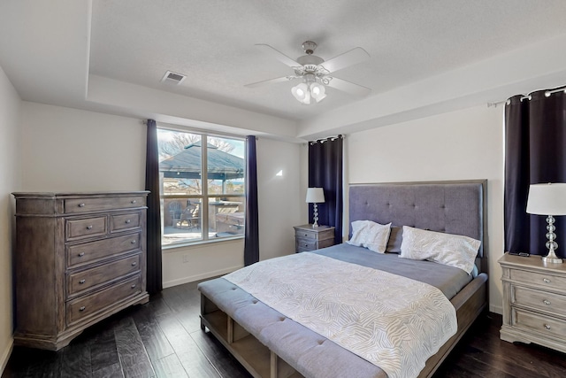 bedroom with ceiling fan, a raised ceiling, and dark wood-type flooring