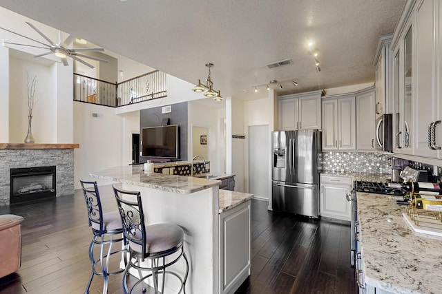 kitchen with light stone countertops, a textured ceiling, stainless steel appliances, a kitchen breakfast bar, and a large island